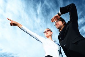 Successful business people standing over blue sky and purposefully looking away.